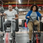 Mies ja nainen harrastivat kuntopyöräilyä kuntosalilla.